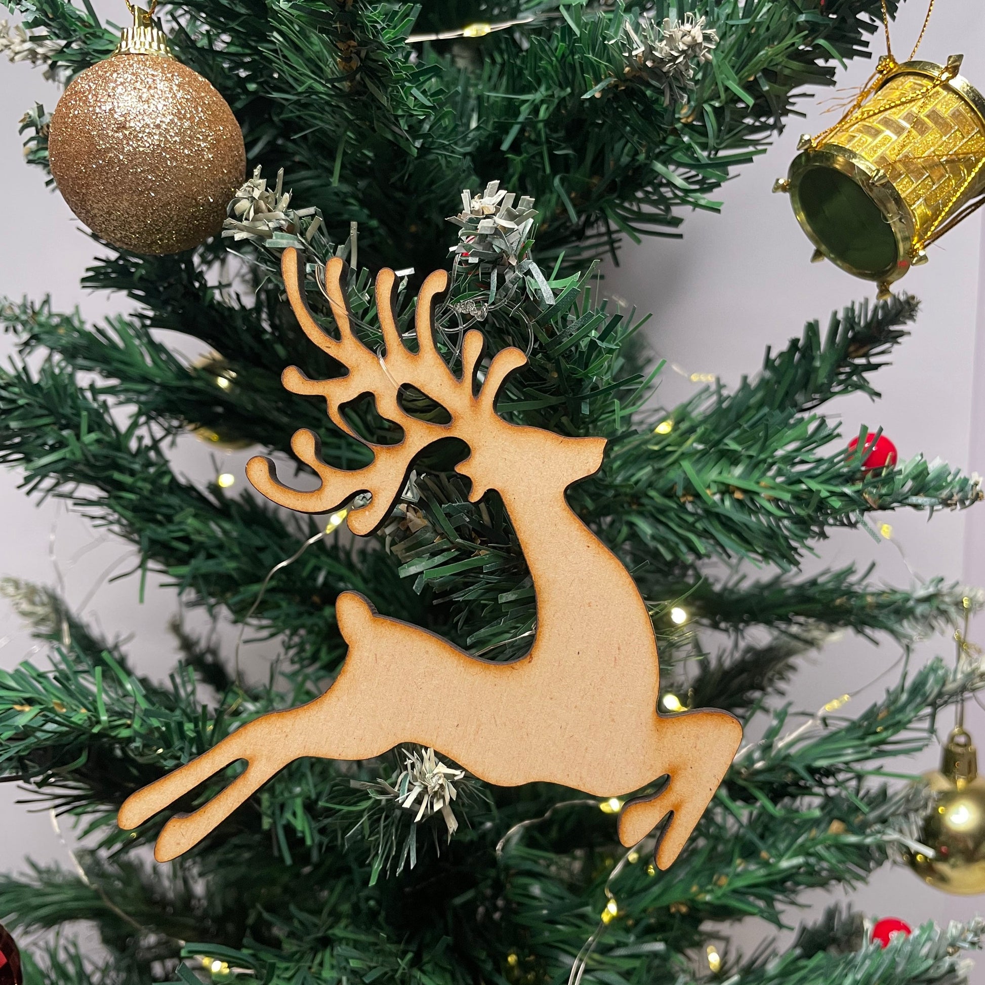 Wooden reindeer ornament on a decorated Christmas tree with lights and ornaments.